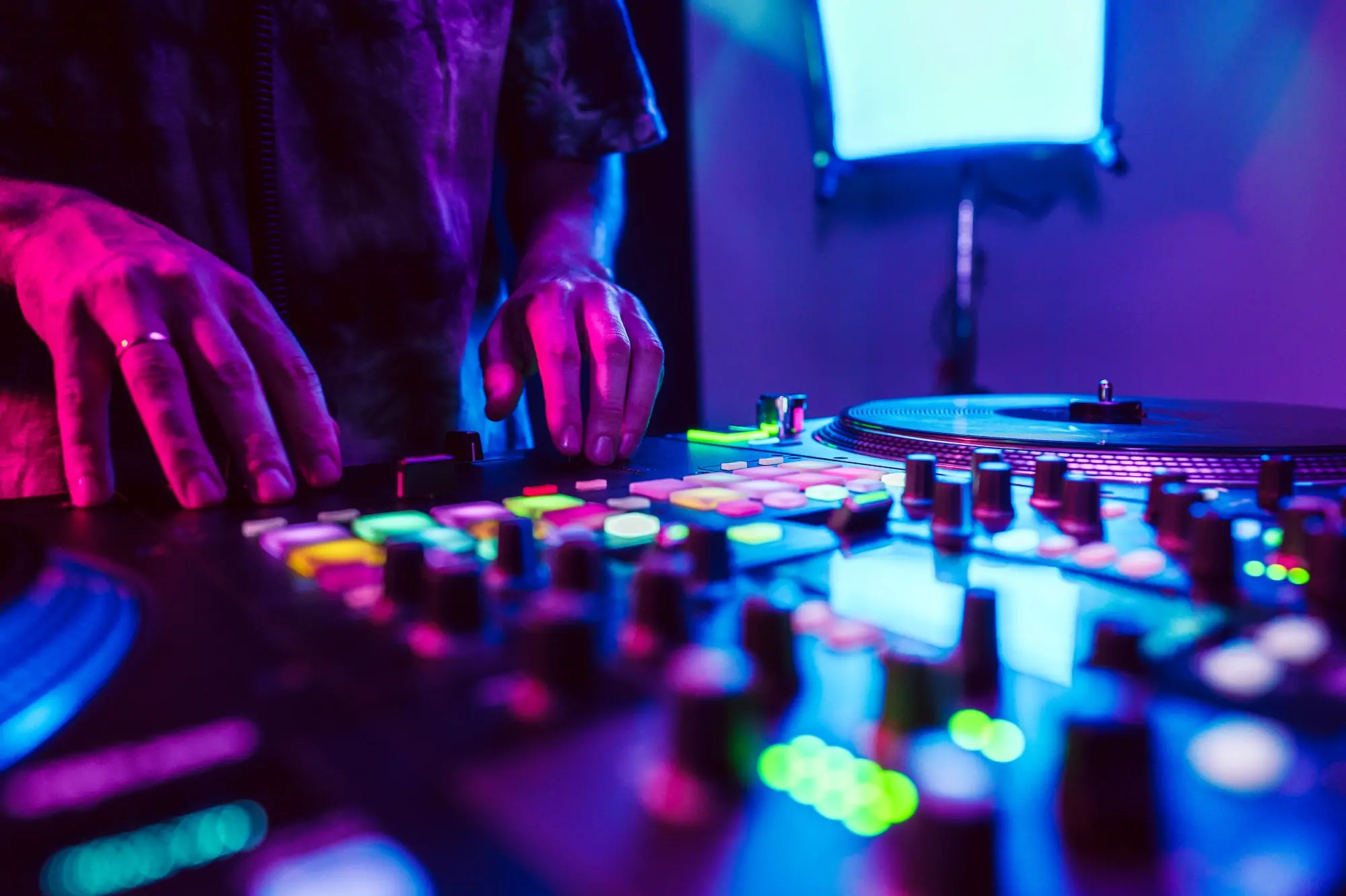 Close up of DJ hands on dj console mixer during concert in the club